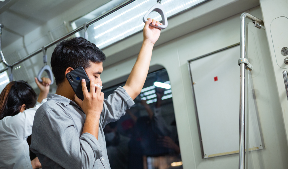 Man holding onto subway while on a phone call